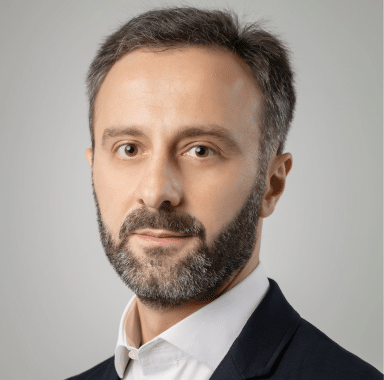 Portrait of Archil Giorgadze in a professional setting, wearing a dark suit and smiling against a neutral background.